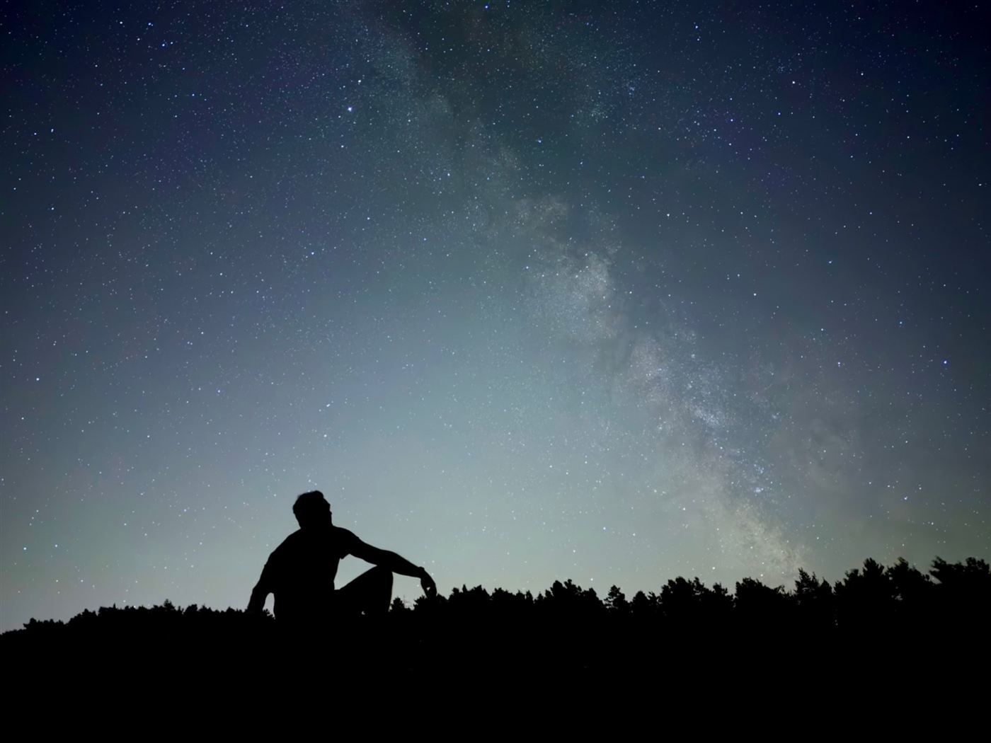 Silhueta de uma pessoa contra o céu estrelado, no Modo Noite